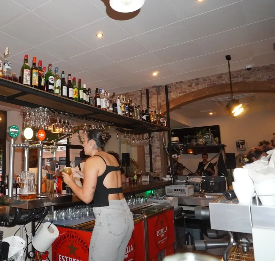 La barra, con las botellas, las copas colgadas y los grifos de cerveza.