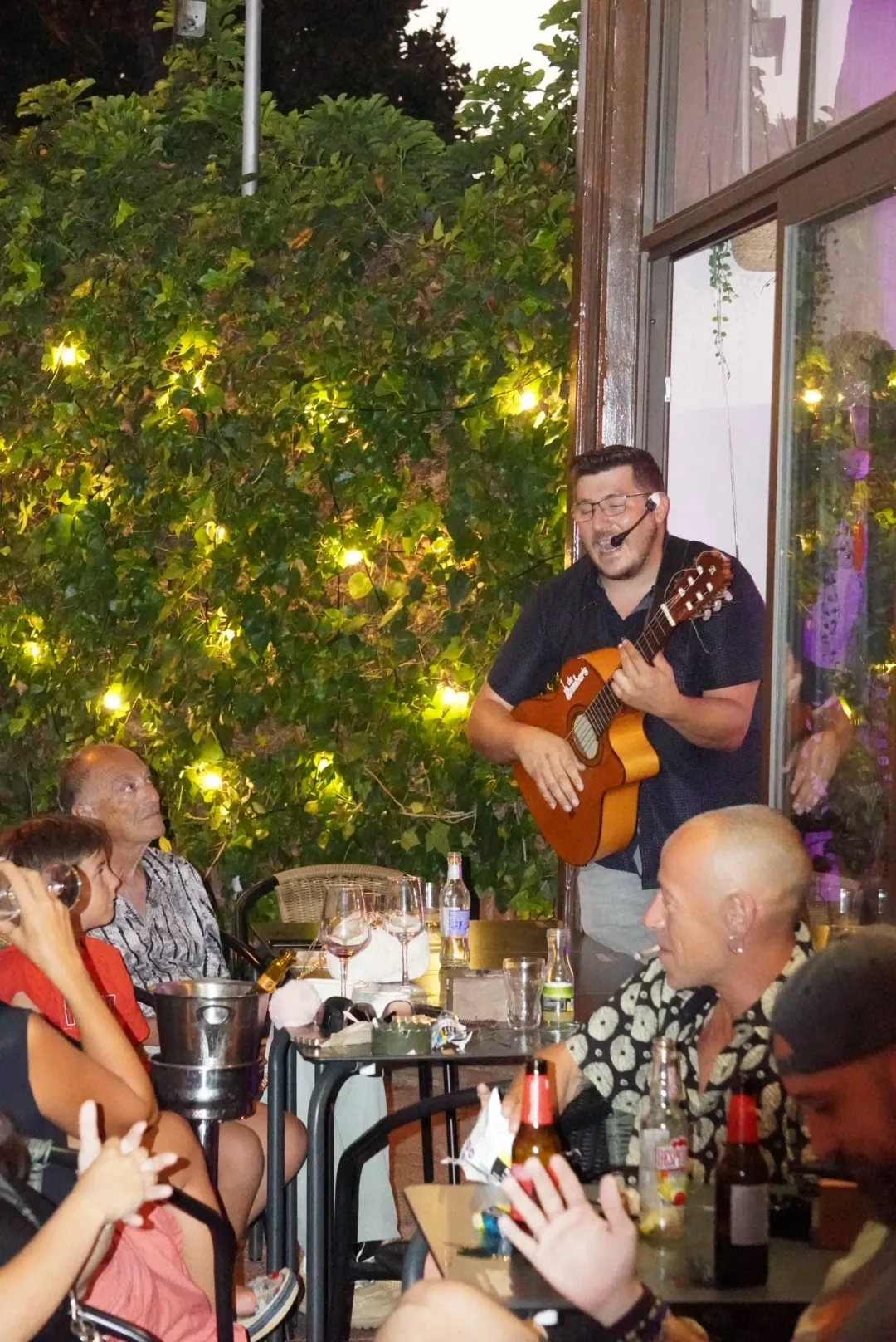 Música en directo en la terraza, bajo la pared de hiedra con luces.